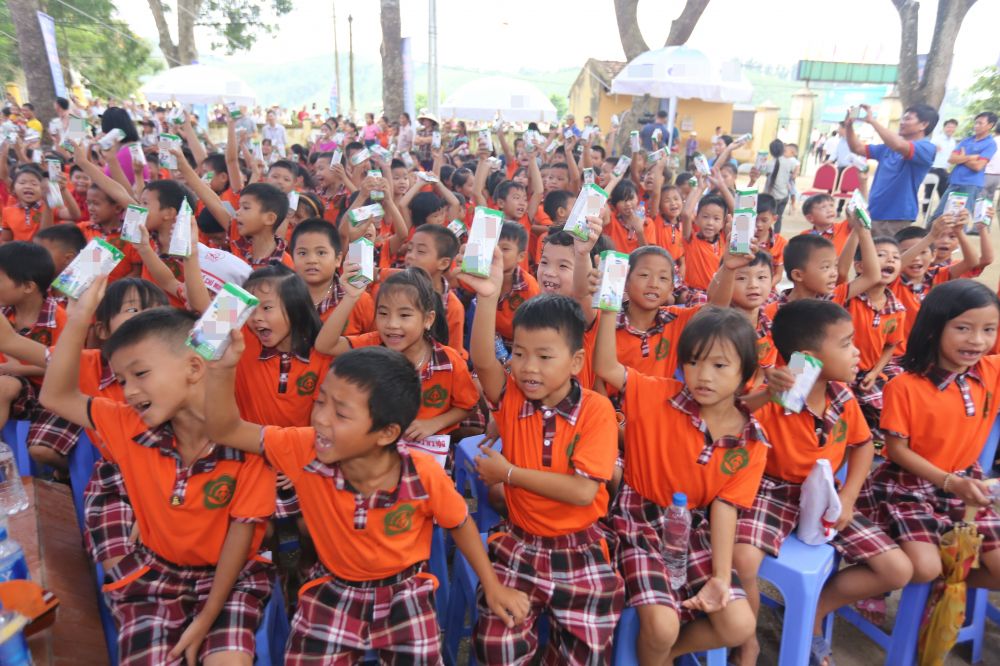 Các em học sinh Việt Nam hào hứng với ly sữa trên tay trong một buổi sinh hoạt tập thể.