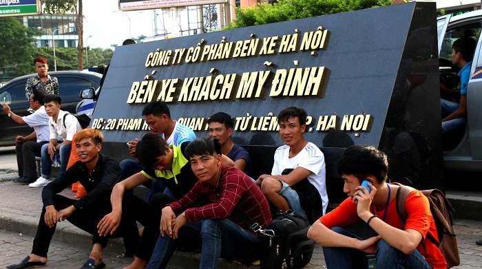 Một nhóm thanh niên chờ xe tại bến Mỹ Đình, lượng người lao động về quê cũng rất đông. 