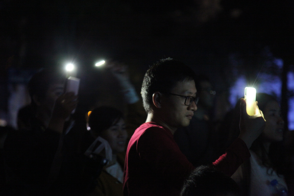 Ánh sáng từ đèn flash của điện thoại của người dân tham dự chương trình được bật lên.