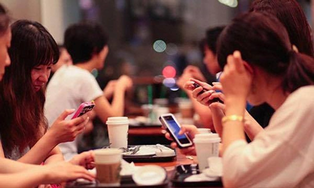 Khi ăn uống điện thoại luôn ở cạnh bên là dấu hiệu cảnh báo bạn bị nghiện điện thoại và mạng xã hội. Ảnh minh họa