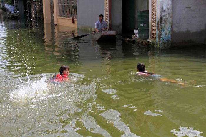 Trẻ bơi lội trong vùng nước ngập ở xóm Bến Vôi - Quốc Oai. (Ảnh: Trường Phong)