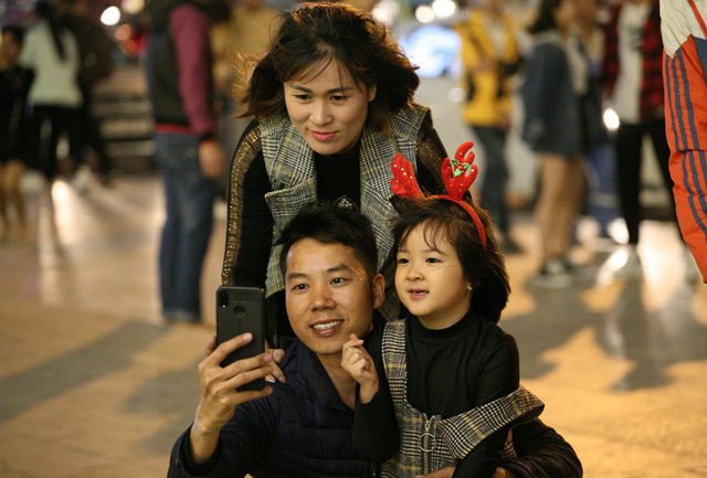  Một gia đình trẻ cho con gái đi chơi, chụp ảnh và hưởng không khí Giáng sinh trong tiết trời se lạnh. 