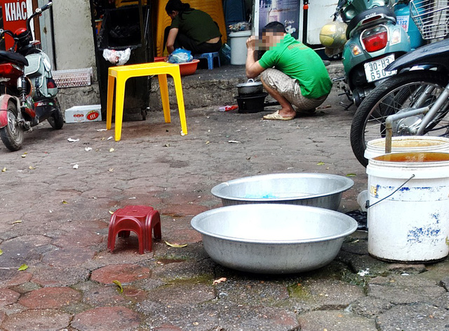 Một quán bún trên phố Hàm Nghi khá nhếch nhác, việc rửa bát đĩa và chế biến thực phẩm ngay tại vỉa hè.