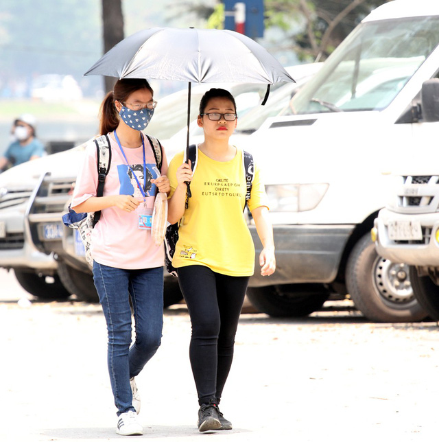 2 thiếu nữ vừa bước từ xe buýt xuống phải vội vàng dùng ô che nắng và cảm thấy vô cùng khó chịu do chênh lệch nhiệt độ cao.