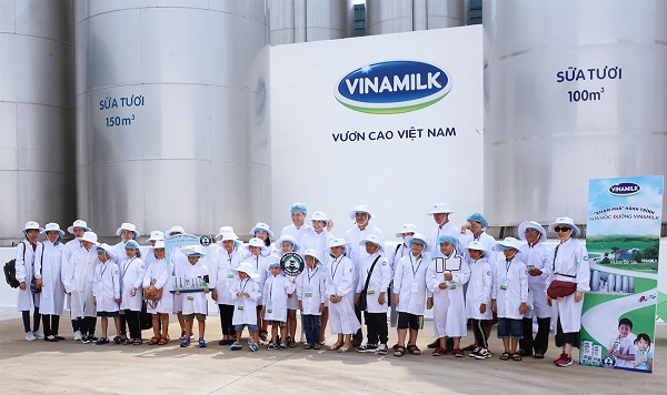 Gia đình diễn viên Mạnh Trường cùng mọi người chụp ảnh trước khu vực bồn chứa sữa tươi khổng lồ của nhà máy.