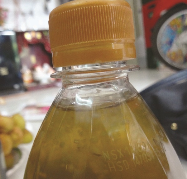 Nắp chai Trà xanh C2 Ô Long Chanh 500ml còn nguyên, đóng chặt nhưng có nhiều hạt và mảng chất lạ nổi lềnh bềnh bên trong.