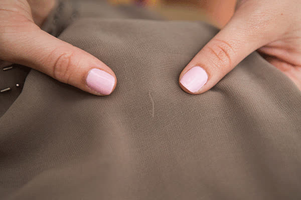 Kéo sợi chỉ bị xù bằng cách kéo dãn vải xung quanh để sợi chỉ về lại vị trí ban đầu.