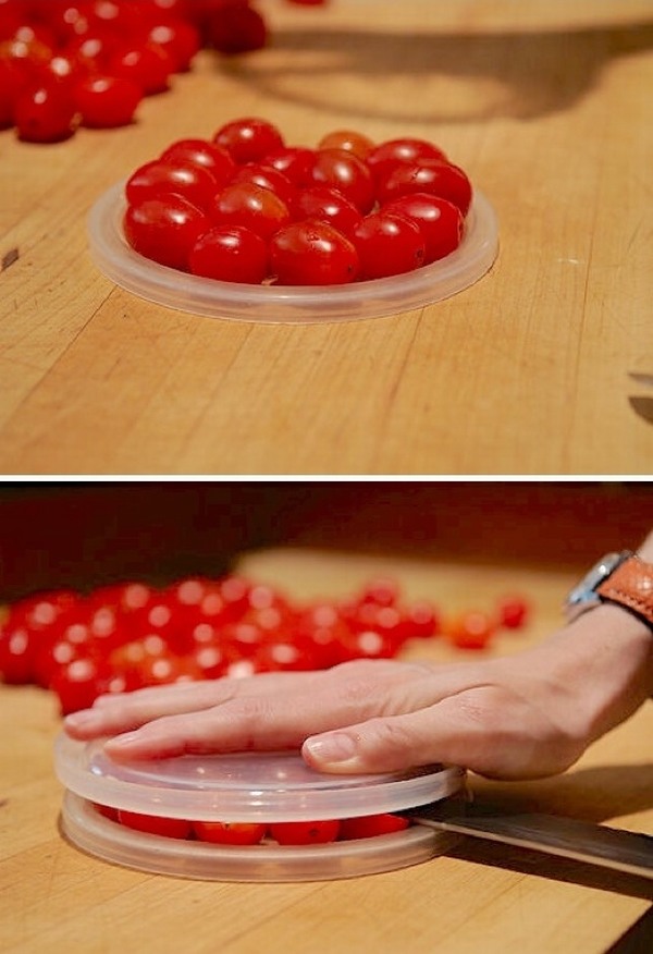 Để cắt đôi thật nhanh cà chua bi, hãy xếp chúng trong một nắp hộp tròn, đè 1 nắp hộp cùng kích cỡ lên trên, giữ chặt phía trên và dùng dao cắt ở giữa.