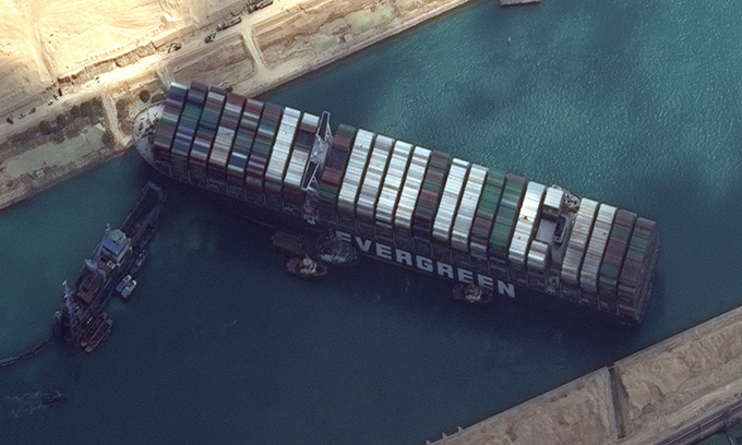 Tàu Ever Given chắn ngang kênh Suez nhìn từ vệ tinh, phía bên trái là con tàu nạo vét cát. Ảnh: AFP