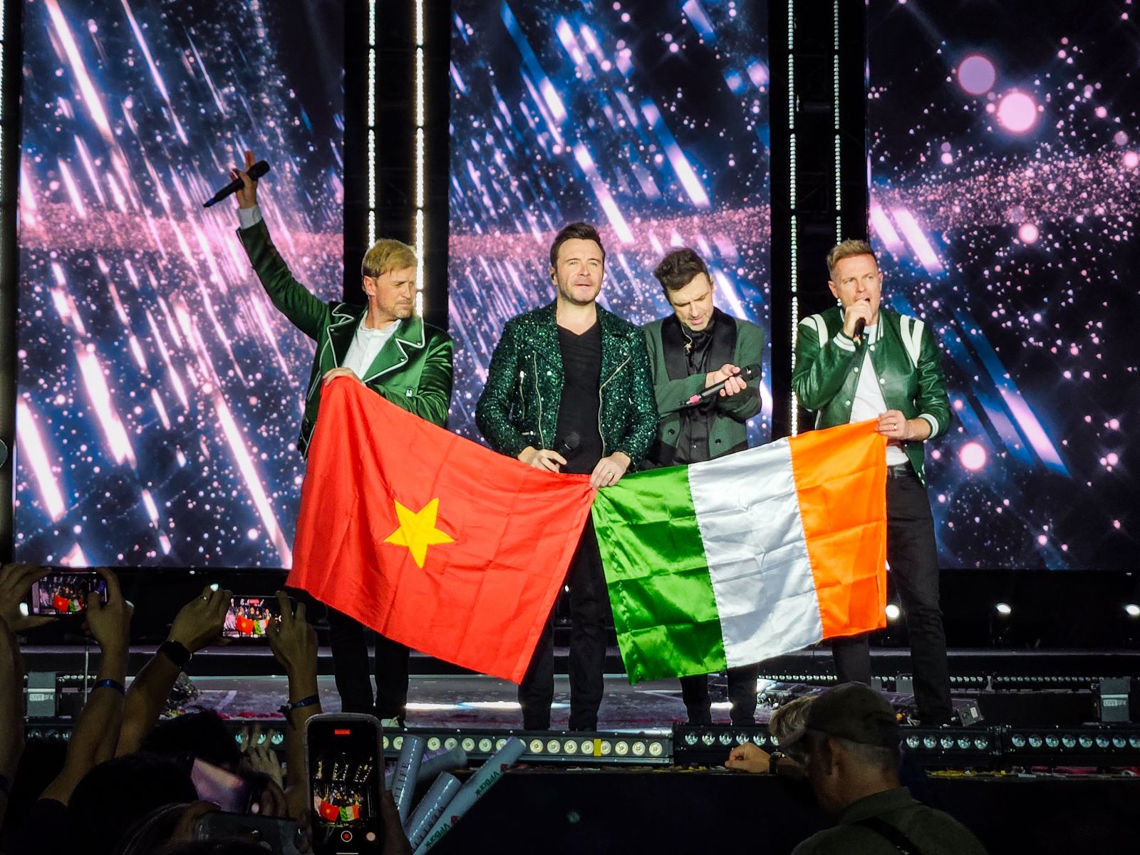 Ban nhạc Westlife trân trọng giương cao lá cờ Việt Nam cùng cờ Ireland và cúi chào khán giả - Ảnh VPBank