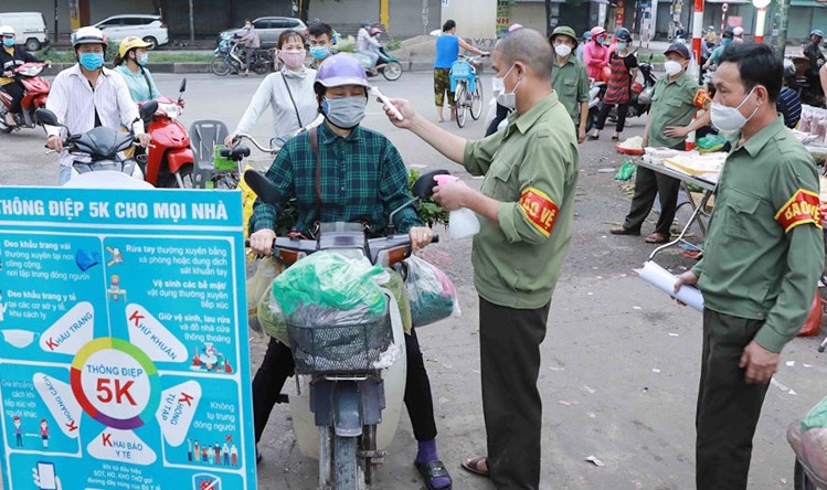Kiểm tra thân nhiệt cho người dân tại chợ đầu mối Minh Khai, quận Bắc Từ Liêm (Ảnh: Vũ Sinh)